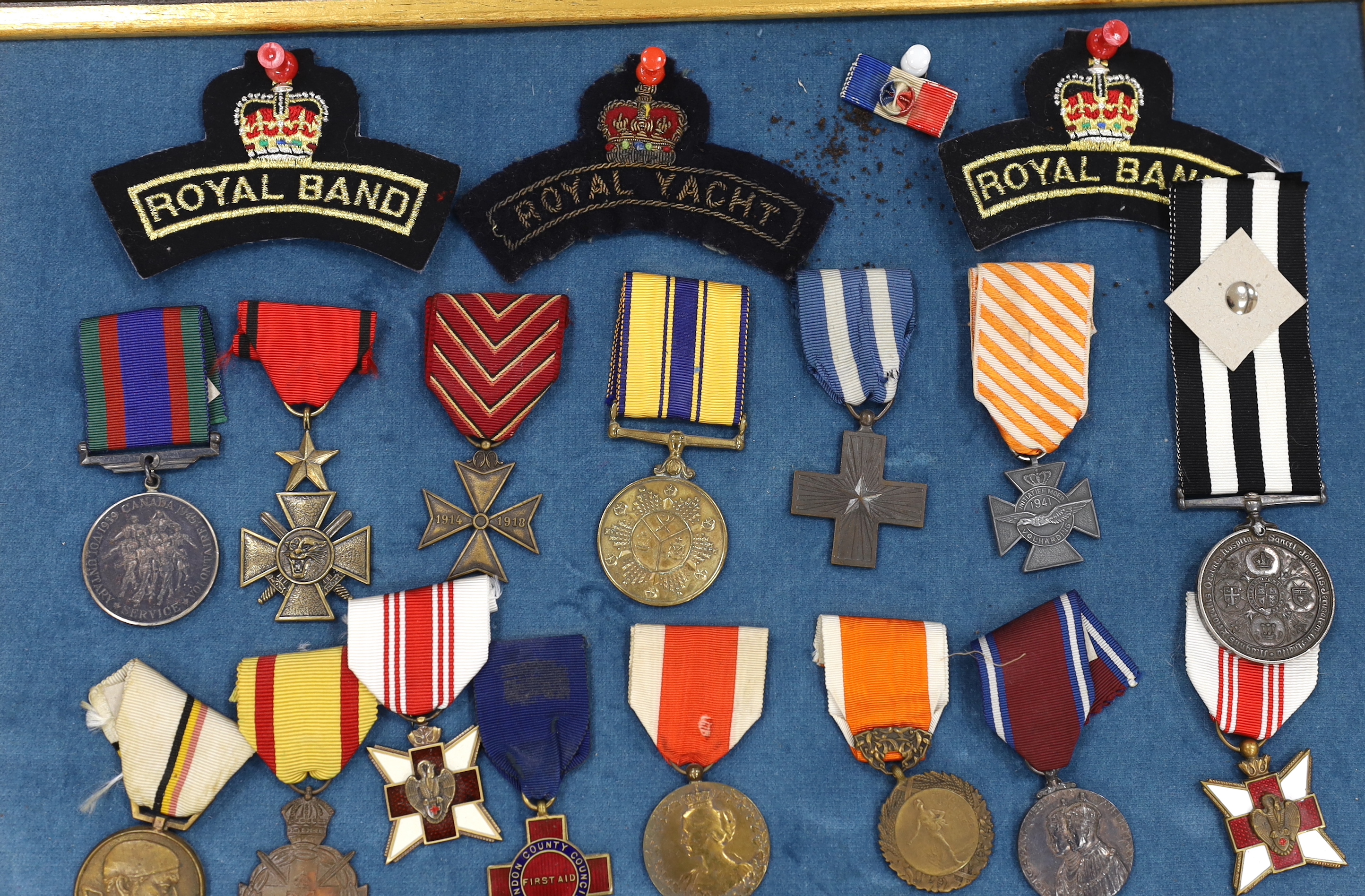 Twenty-seven medals and awards mounted in oak frames, including; French 1939-45 War Medal, Poland Lenino Cross 1943, Romanian Commemorative Medal, Belgium Red Cross Medal, etc. together with cloth shoulder titles for the